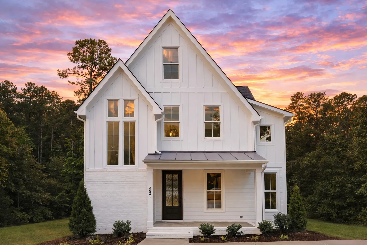 Front elevation of a Modern Farmhouse and New American style home featuring board and batten siding, steep gable rooflines, and a welcoming covered porch