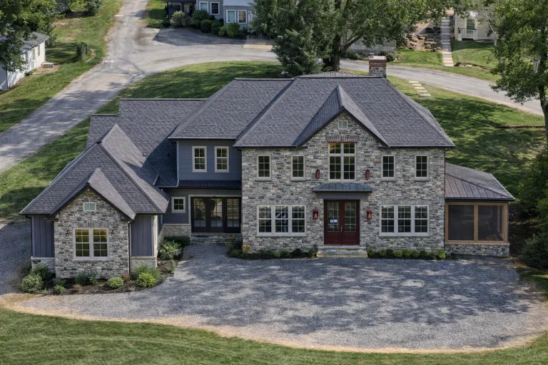 Front elevation of a Traditional Colonial Revival home with brick exterior, symmetrical windows, black shutters, and covered side porch