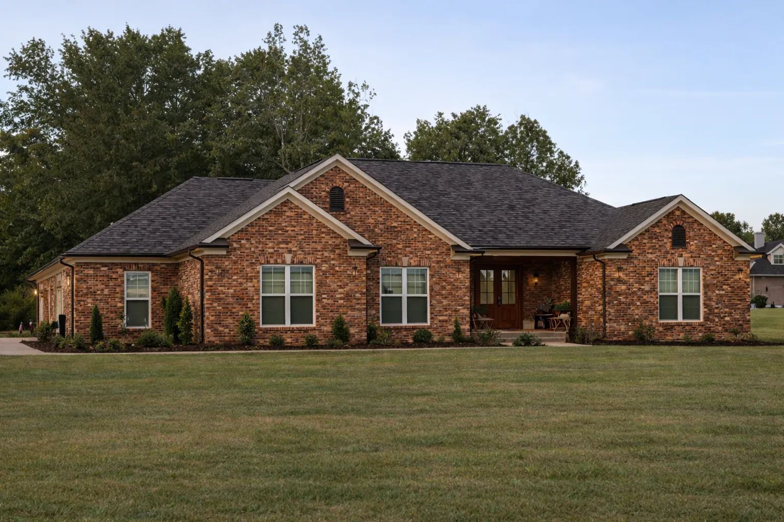 Front view of a Traditional Ranch style home with classic brick exterior, white trim, and black shutters surrounded by manicured landscaping.