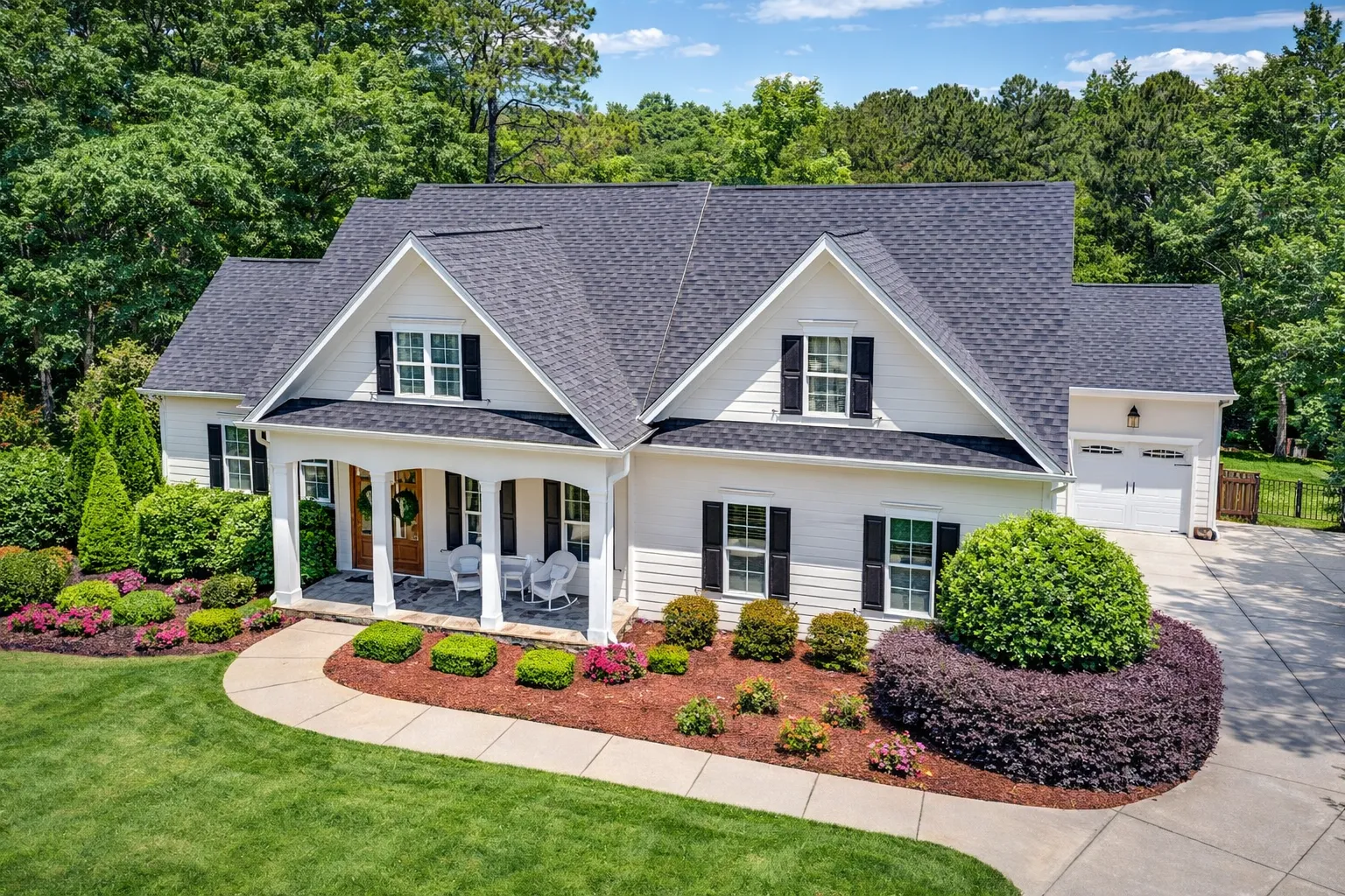Southern Farmhouse style home with horizontal siding, gabled rooflines, covered front porch, and traditional suburban landscaping