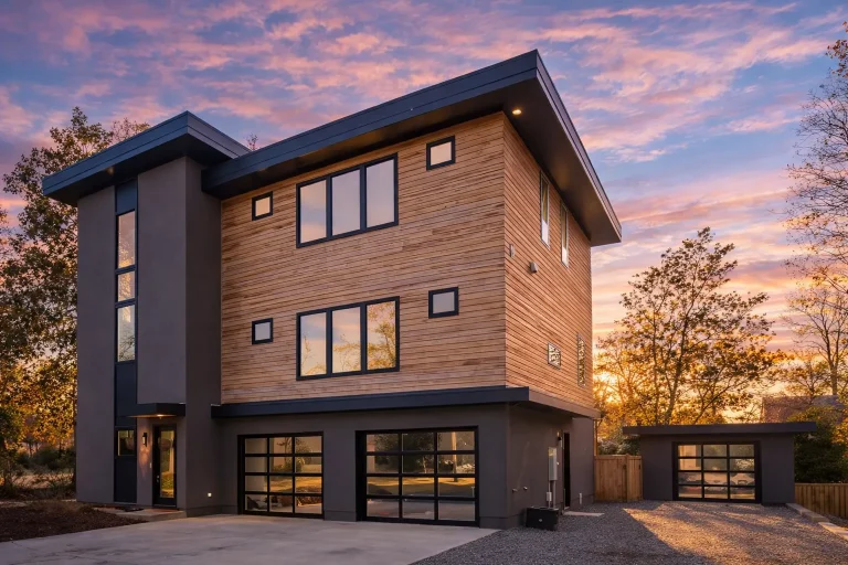Front elevation of an Urban Contemporary Modern house with smooth stucco tower, horizontal lap siding, black-framed windows, and a two-car garage on a three-story narrow-lot design