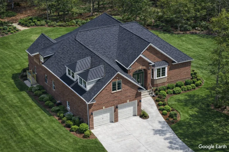 Aerial front view of a Traditional Neo-Colonial brick home with hip roof, side-entry garage, manicured landscaping, and classic suburban design