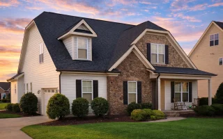 Front exterior view of a Traditional Suburban New American style home with mixed stone veneer, horizontal siding, gabled rooflines, and covered porch