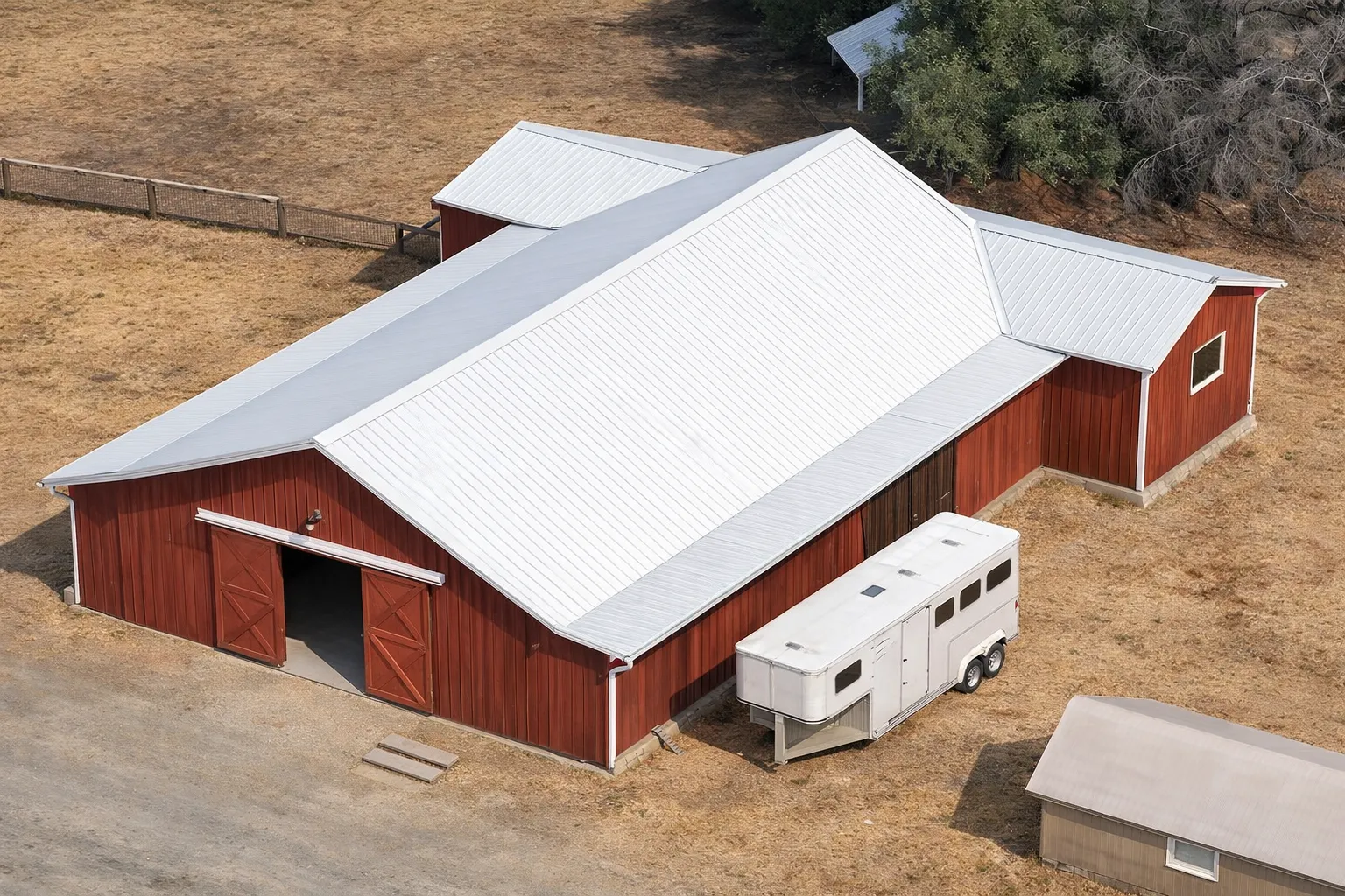 Front elevation of a barn house style structure with board and batten siding, metal roof, and large central barn doors in a rural setting