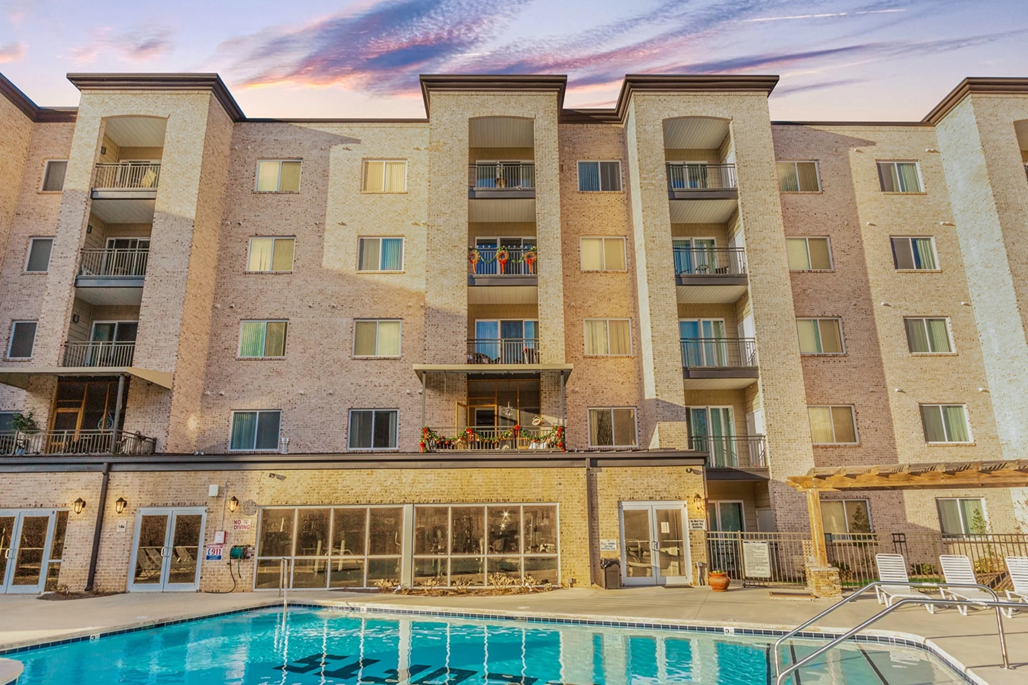 Front elevation of contemporary urban apartment building with brick exterior, stacked balconies, and modern detailing