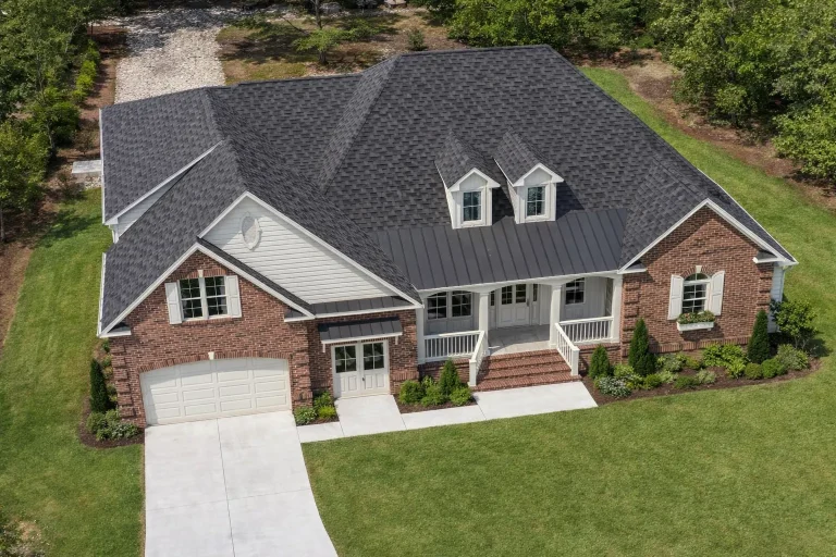 Front exterior view of a Traditional New American style home with brick facade, horizontal siding, covered porch, and symmetrical rooflines