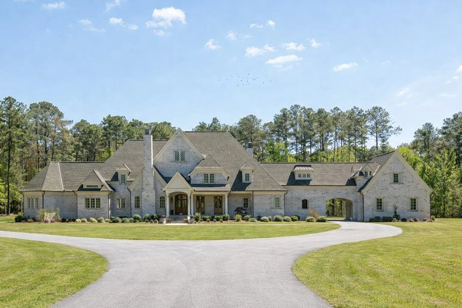 Front elevation of a Traditional New American suburban house featuring stone entry, painted brick accents, lap siding, and a symmetrical roofline