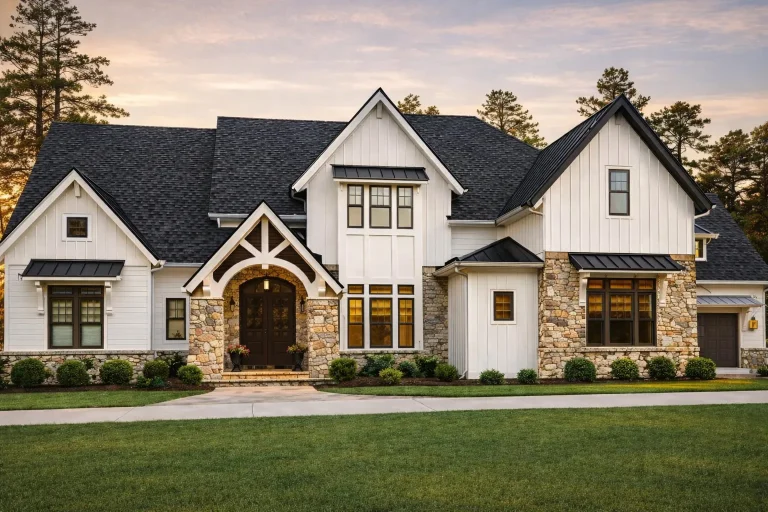 Front elevation of a modern farmhouse home with white board-and-batten siding, stone accents, steep gables, and a covered entry.