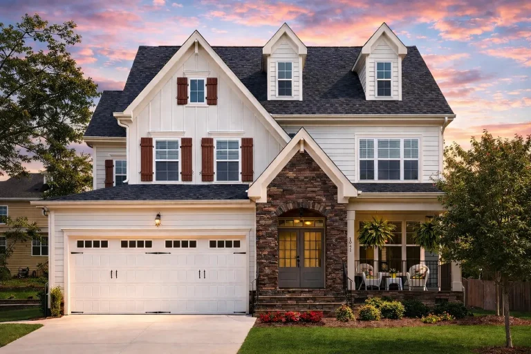 Front exterior view of a New American Colonial style home with horizontal siding, stone entry, symmetrical windows, and attached two-car garage