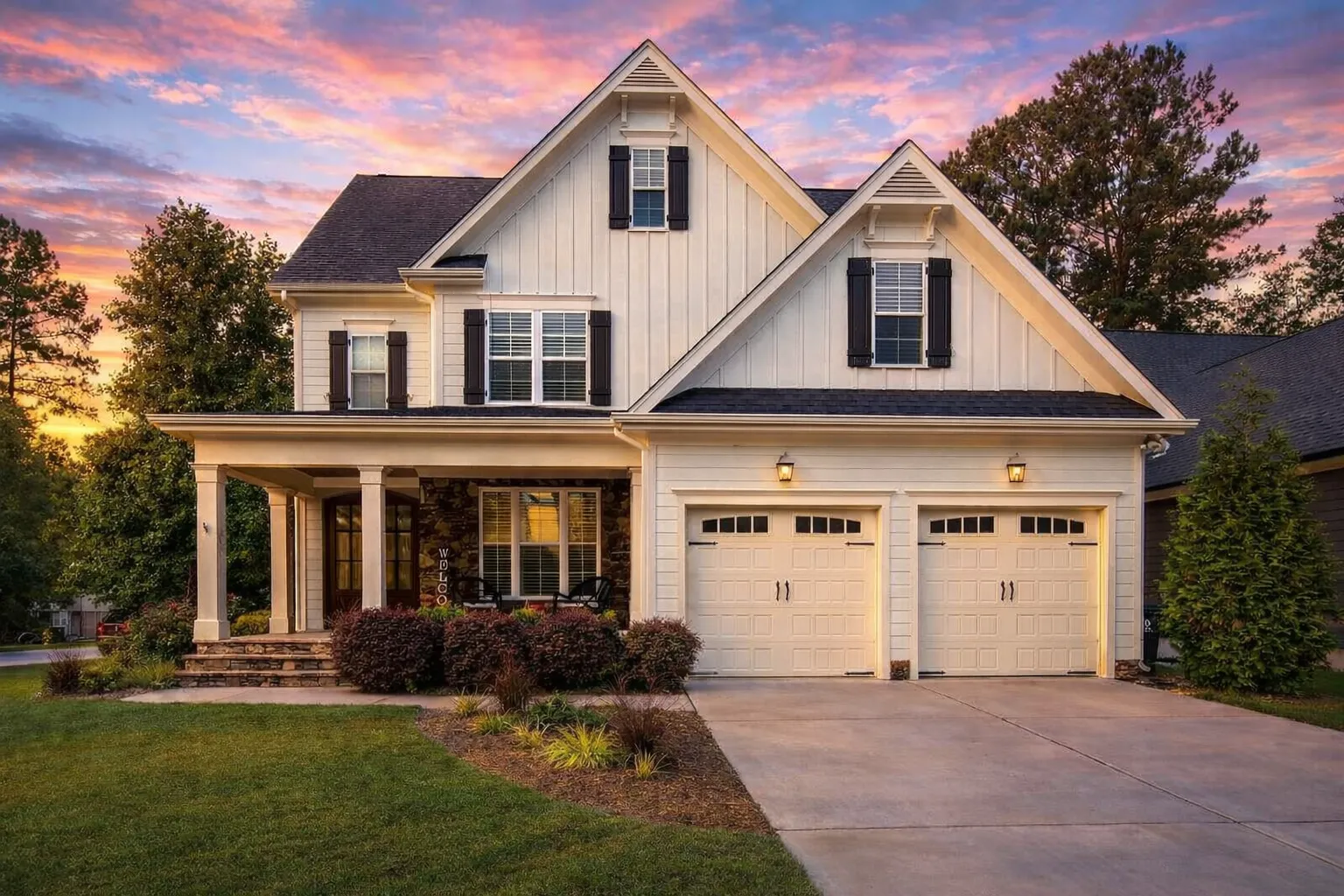 Front elevation of a New American farmhouse style home featuring board and batten siding, gabled rooflines, black shutters, and a welcoming covered porch