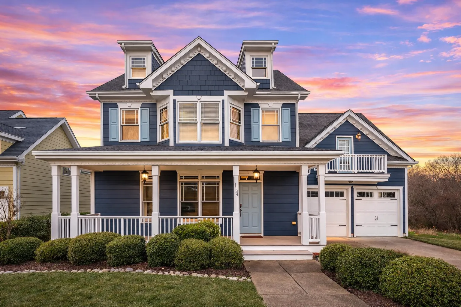 Front elevation of a Neo-Colonial / Traditional Colonial home with horizontal lap siding, stone veneer accents, black shutters, dormers, and a welcoming covered porch