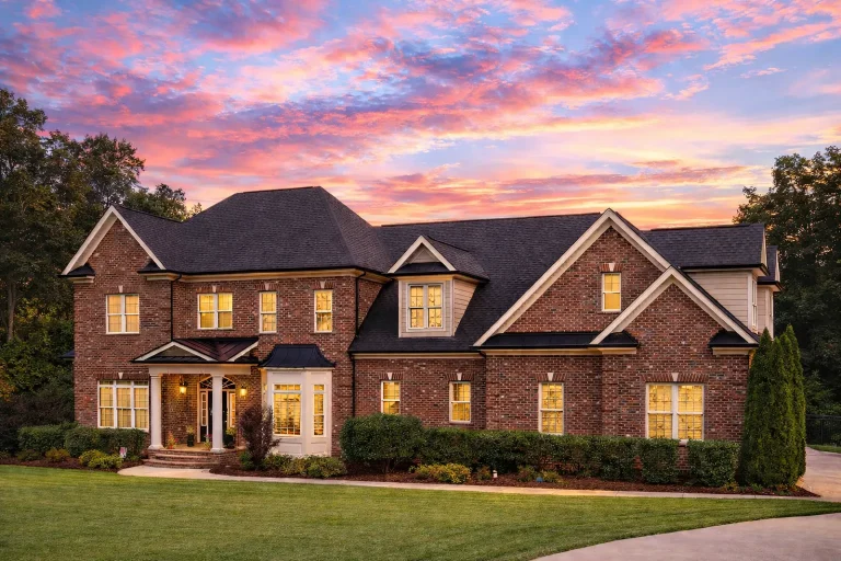 Front elevation of a Traditional Colonial style home with brick and stone exterior, symmetrical windows, shutters, and a classic centered entry