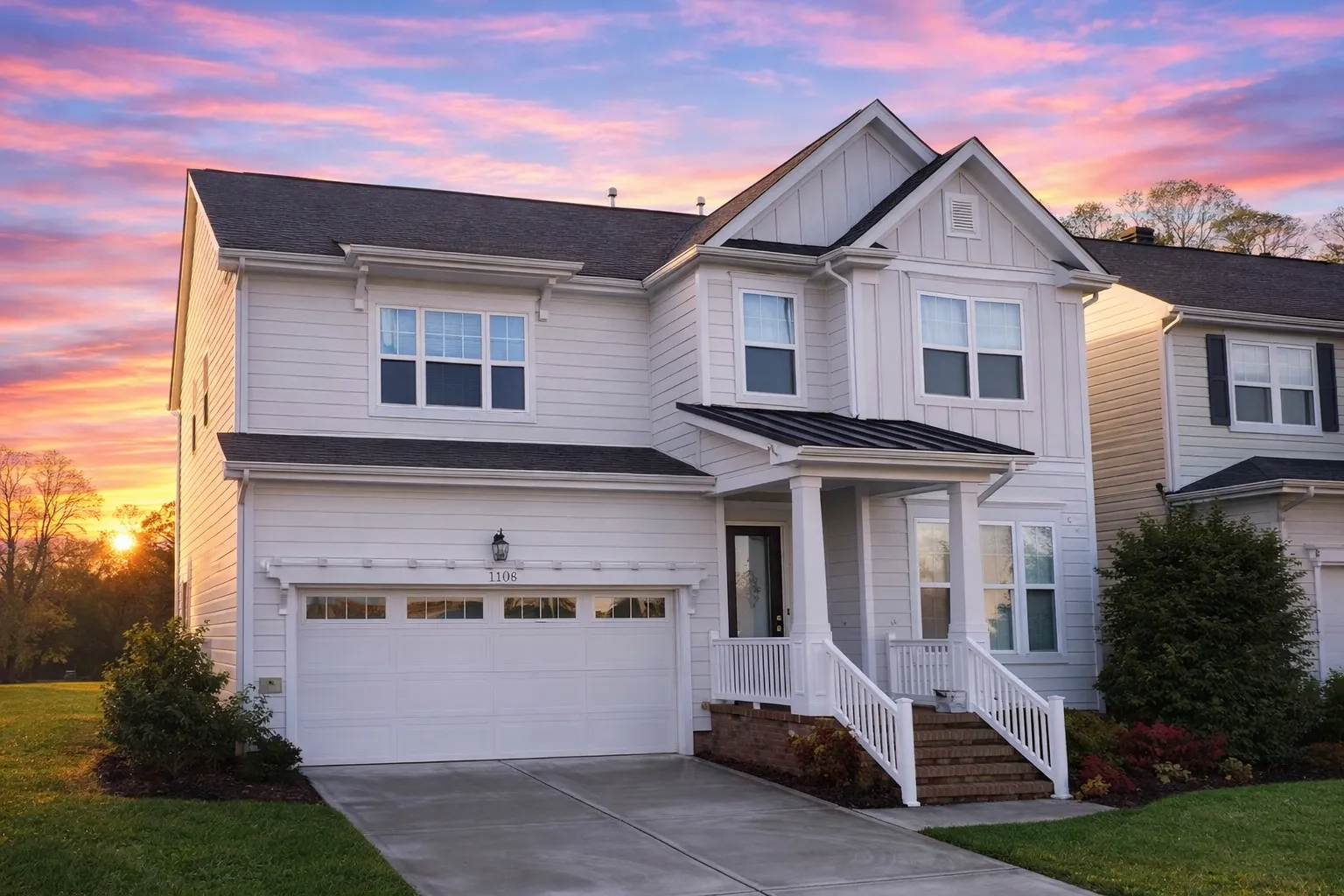 Front elevation of a Traditional Colonial style home with brick and horizontal siding, symmetrical windows, and a two-car garage