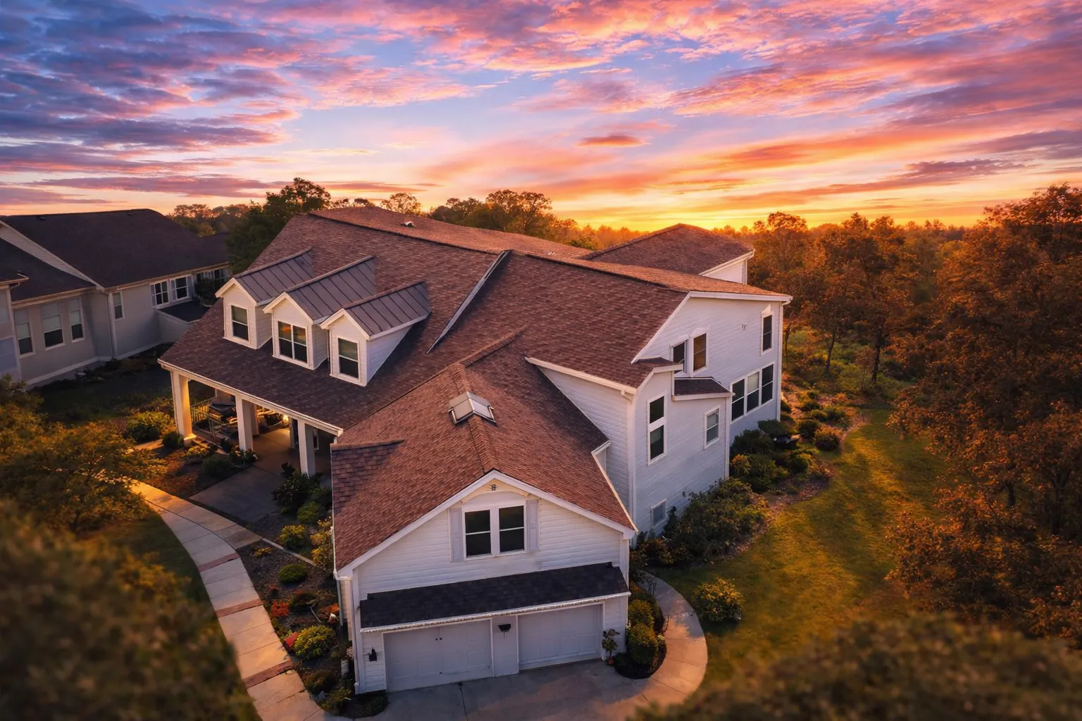 Front view of a Traditional Farmhouse style home featuring horizontal siding, stone accents, gabled dormers, and a welcoming covered porch entry