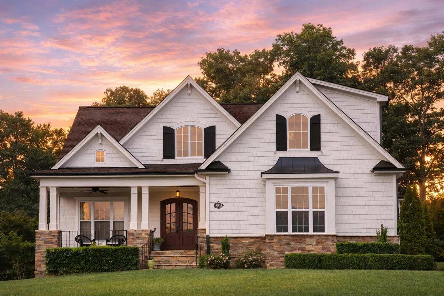 Front elevation of a New American style home with brick and stone exterior, board and batten siding, steep gabled roof, and covered front porch