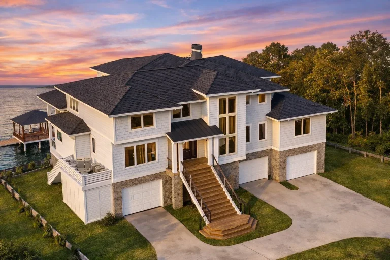 Front exterior of luxury Coastal Beach House with smooth stucco, lap siding accents, multiple garages, and elevated entry staircase