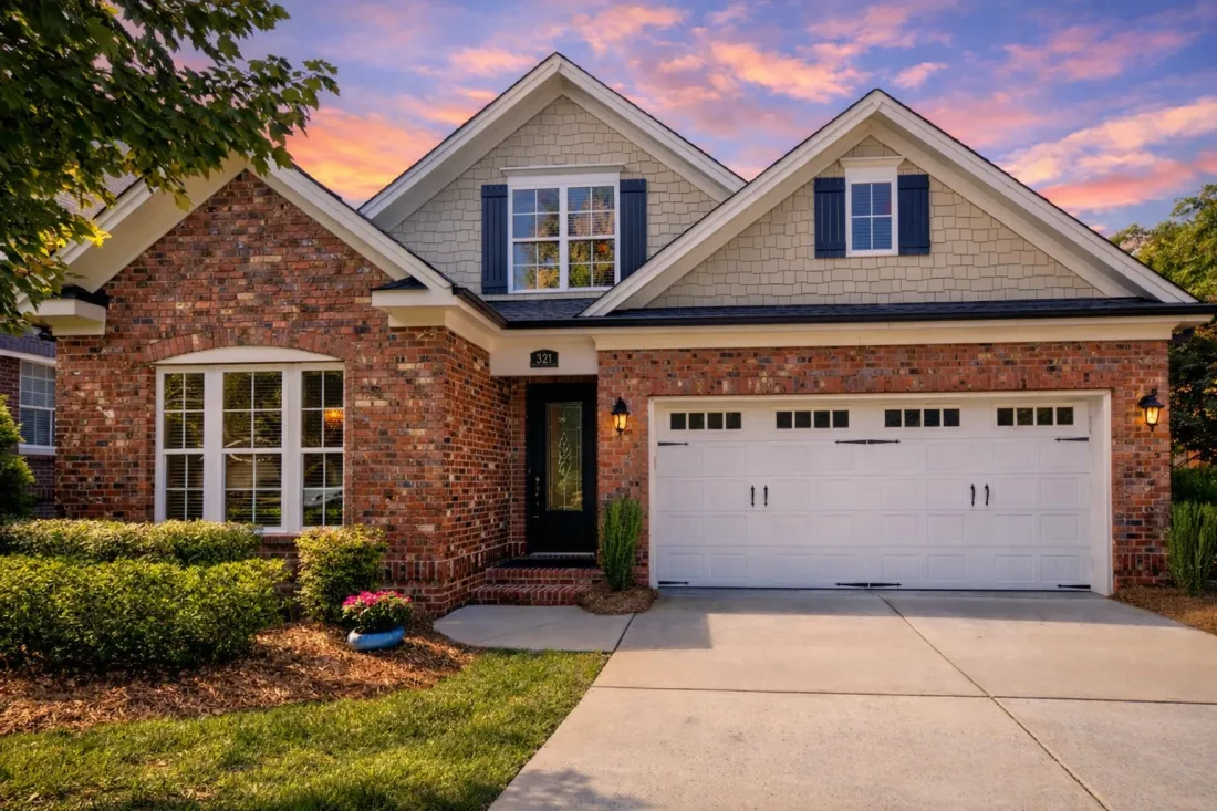 Front elevation of Traditional Colonial Revival style home with brick exterior, lap siding gables, and two-car garage