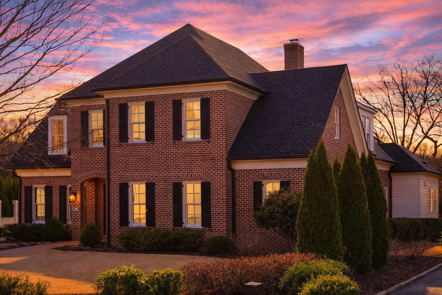 Front elevation of a Traditional Colonial style brick home with symmetrical windows, black shutters, and a centered entry