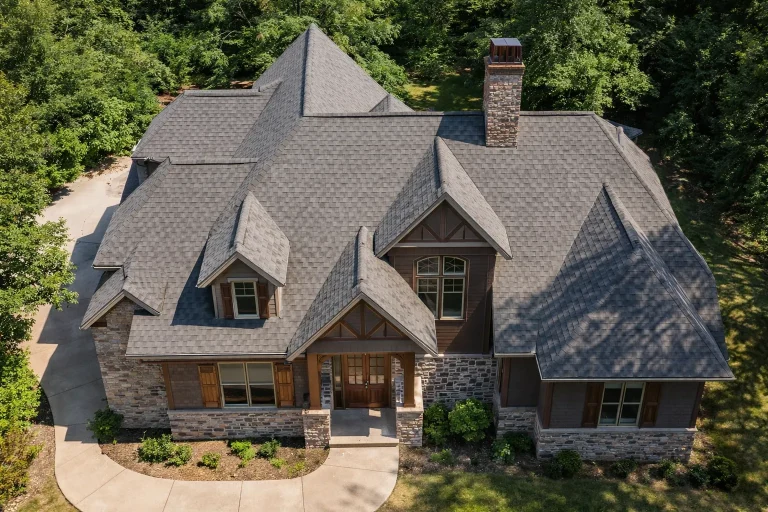 Front elevation of a New American modern traditional house featuring stone veneer, horizontal siding, steep gabled rooflines, and a welcoming covered entry