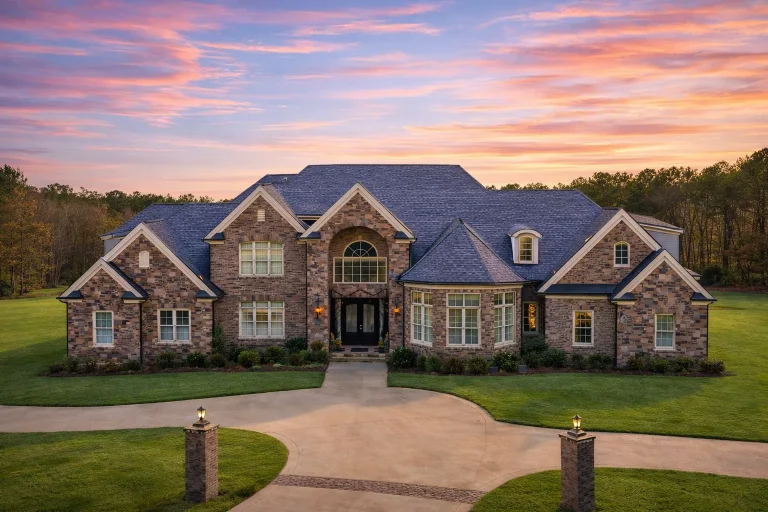 Front elevation of a New American Traditional style house with brick and stone exterior, symmetrical design, arched entry, and manicured landscaping