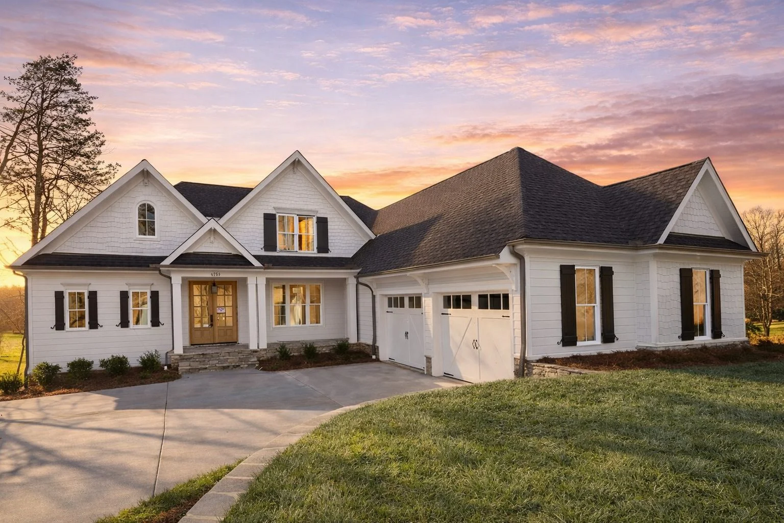 Front elevation of traditional classic suburban house with horizontal lap siding, shake gables, covered entry porch, and symmetrical windows