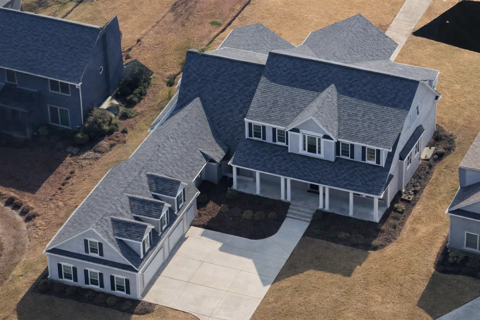 Front elevation of a Traditional Colonial style home featuring horizontal siding, brick foundation accents, symmetrical windows, and a full-width covered porch