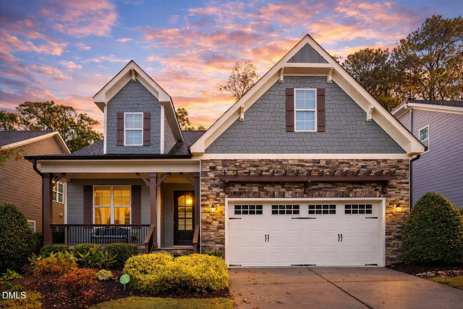 Front elevation of a New American Cape Cod style home with shingle siding, stone accents, dormer windows, and a two-car garage