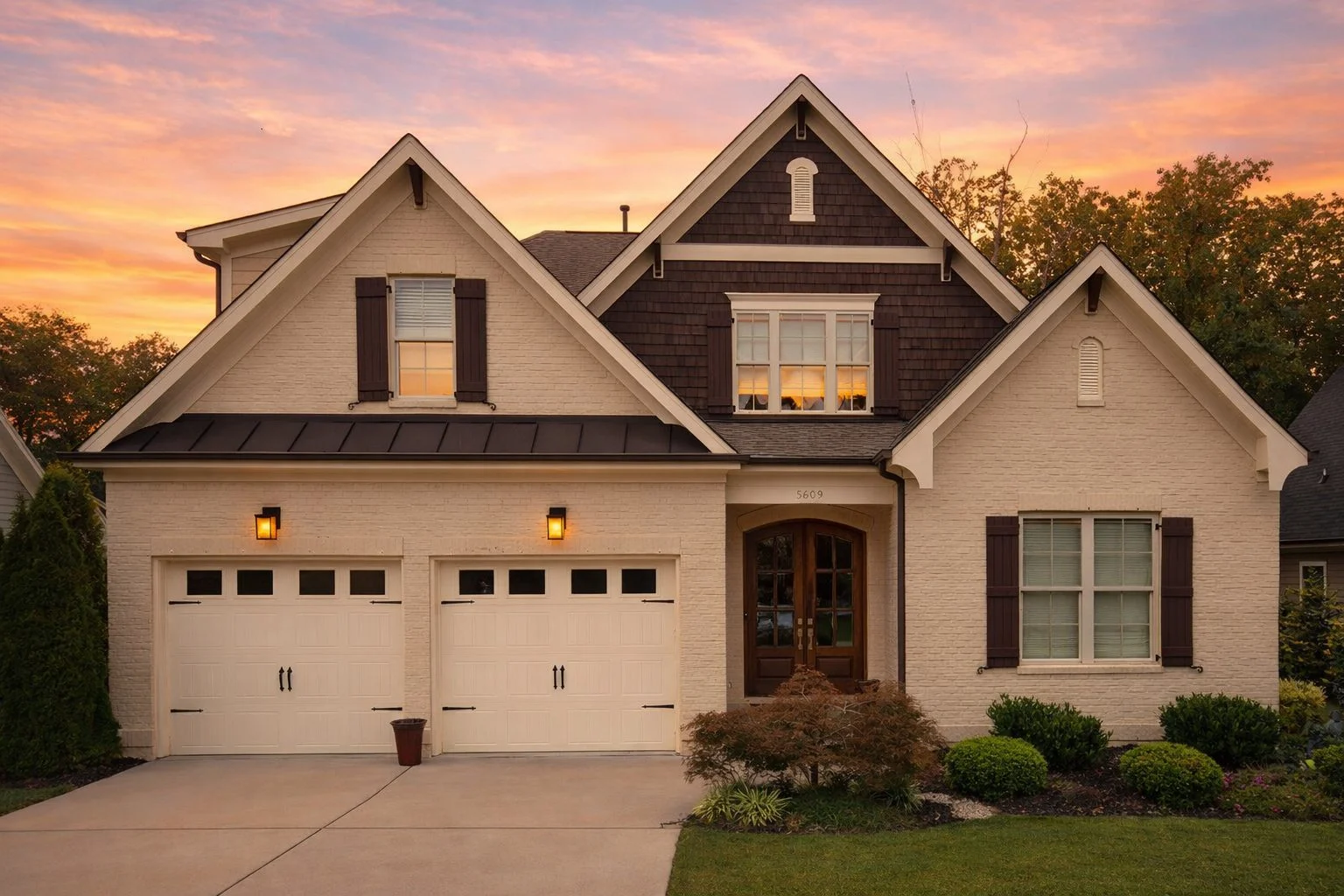 Front elevation of a New American style home with brick and siding exterior, wood shutters, steep gable roof, and double garage