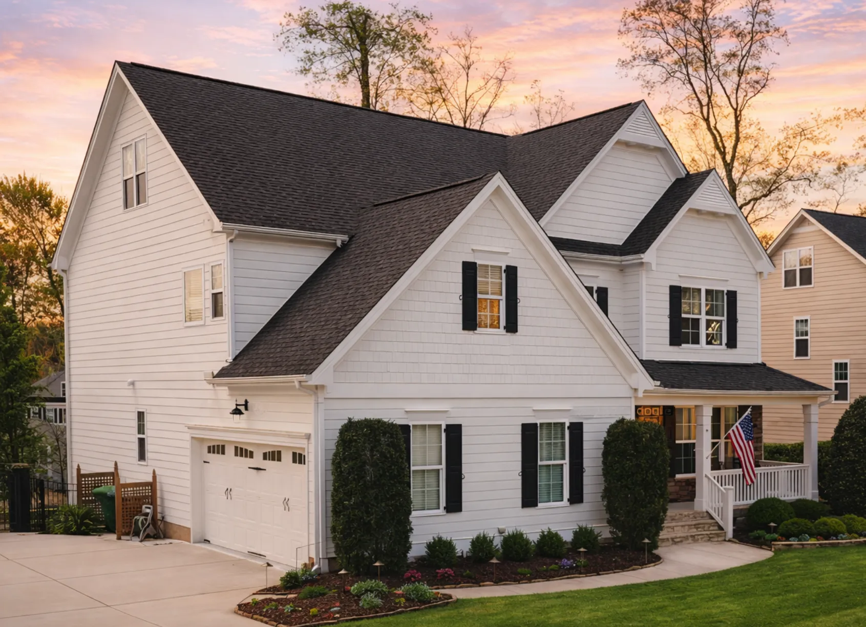 Front exterior view of a New American modern traditional home featuring horizontal siding, stone-accented garage, covered porch, and classic suburban curb appeal