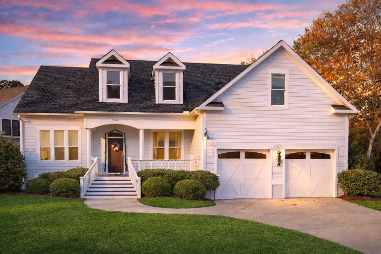 Front elevation of a modern farmhouse style home with horizontal siding, black garage doors, covered porch, and symmetrical rooflines