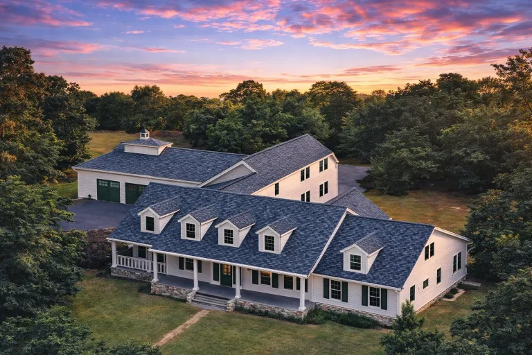 Front elevation of a Colonial Cape Cod style home featuring symmetrical windows, dormer rooflines, lap siding exterior, and a welcoming covered front porch
