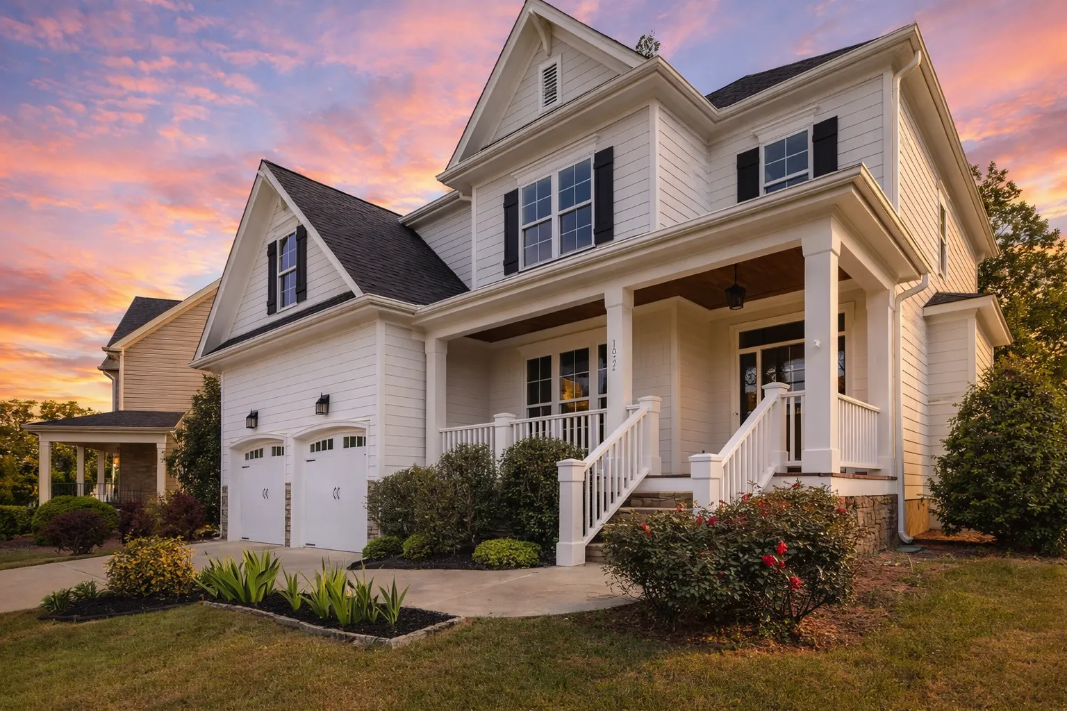 Front elevation of a coastal shingle style house with blue horizontal siding, shingle accents, dormer windows, and an attached two-car garage
