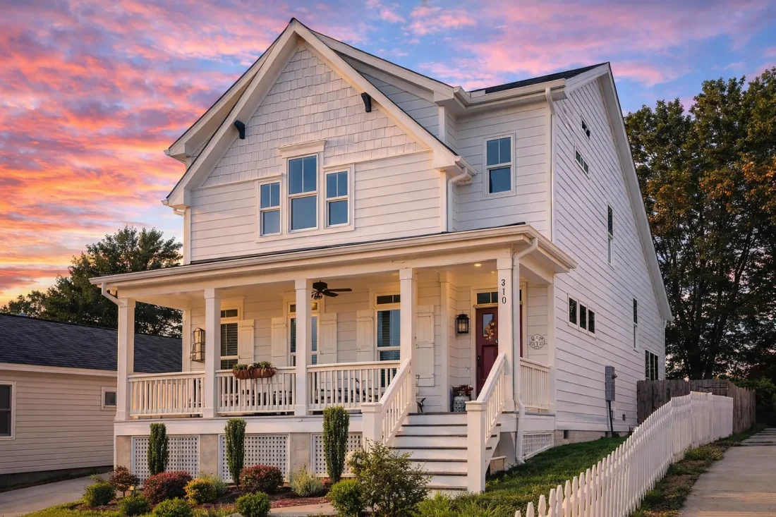 Front elevation of Traditional Colonial style home with white horizontal lap siding, covered front porch, and classic symmetrical windows