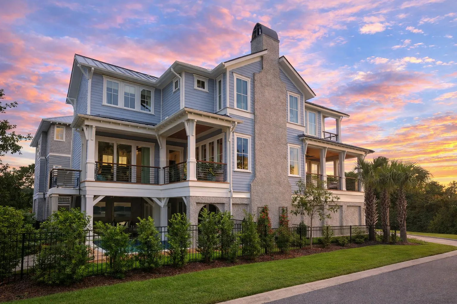Front elevation of an elevated Coastal Beach House with horizontal siding, multiple covered balconies, ground-level garage, and Low Country coastal architecture