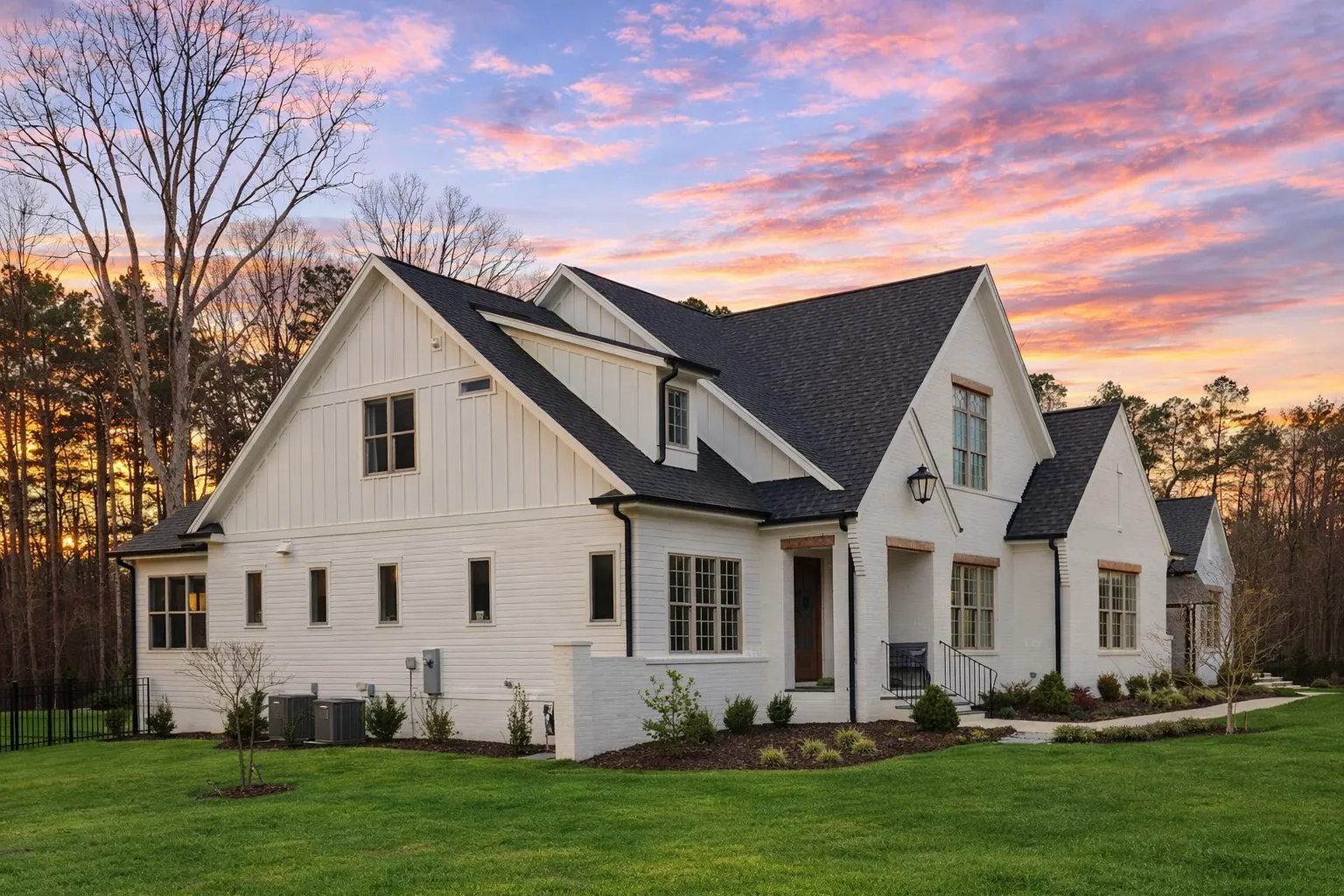 Front elevation of a New American Traditional style house featuring painted brick, horizontal siding, gabled rooflines, and an attached garage