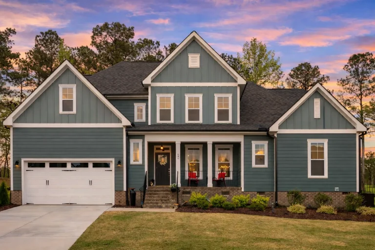 Front elevation of a Traditional Colonial style home featuring horizontal and shingle siding with stone accents and a welcoming covered porch