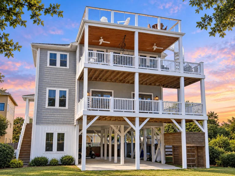 Front exterior view of an elevated Coastal Beach House featuring stacked wraparound porches, horizontal siding, and Southern Low Country architecture