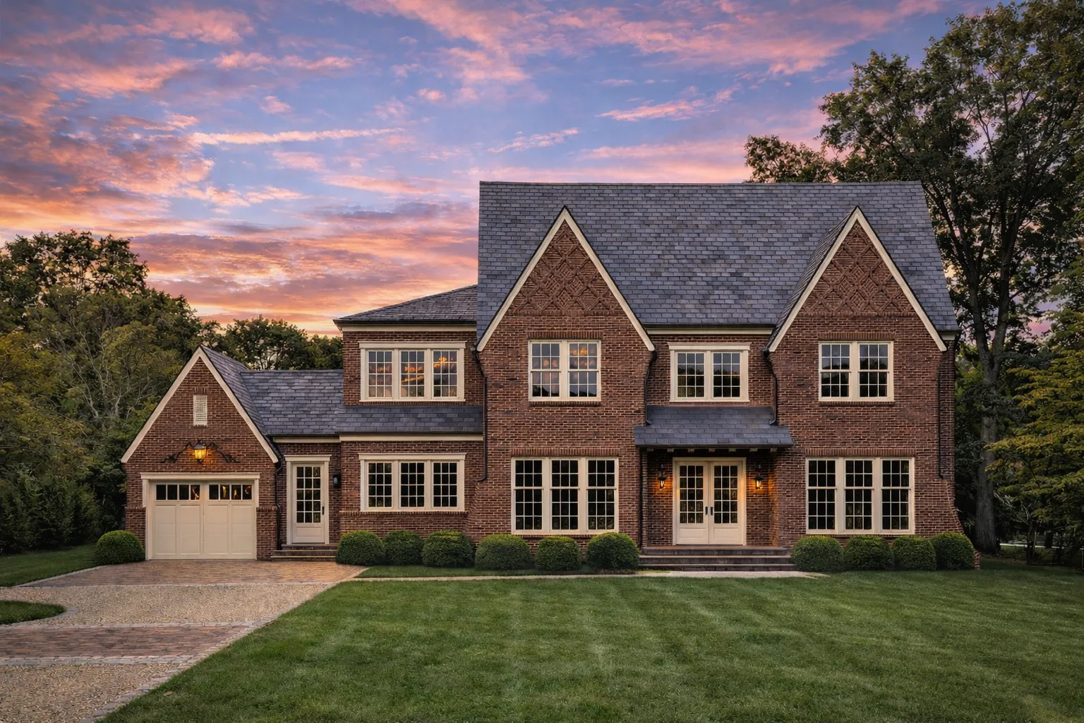 Front elevation of Traditional Colonial style house with red brick exterior, symmetrical windows, gabled rooflines, and covered entry porch