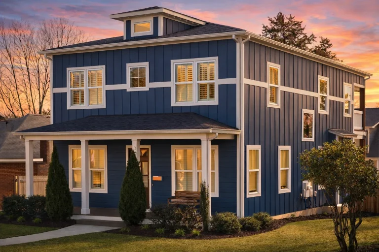 Front elevation of an American Foursquare style home featuring lap siding, board and batten accents, symmetrical windows, and a covered front porch
