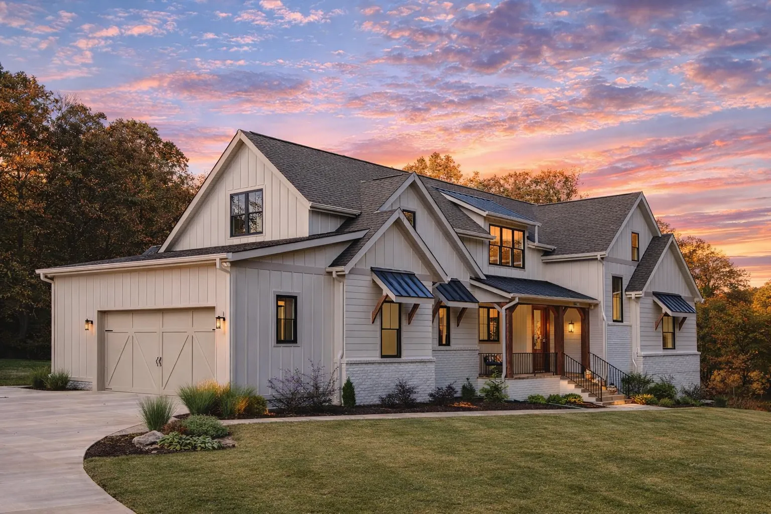 Front exterior of a Modern Farmhouse style home with white board and batten siding, black windows, covered porch, and attached garage at sunset