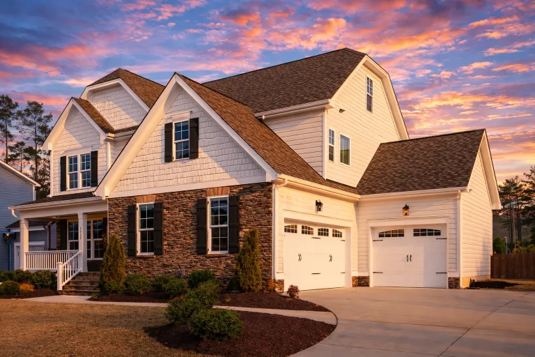Sloping Lot House Plans 8 Front elevation of New American Traditional style home with stone veneer, lap siding, shake accents, and two-car garage