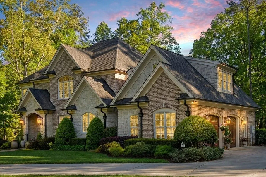 Front elevation of a New American modern traditional house with brick exterior, stone accents, horizontal lap siding, arched entry, and side-entry garage