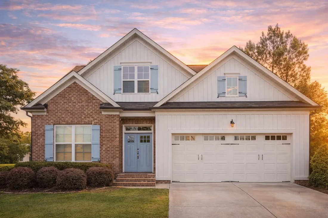 Front elevation of a modern traditional suburban home with brick exterior, board and batten siding, gabled rooflines, and two-car garage