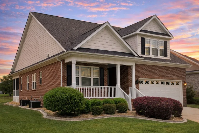 Front elevation of a Traditional Colonial style home featuring a stone and horizontal siding exterior, gable rooflines, and welcoming front porch entry