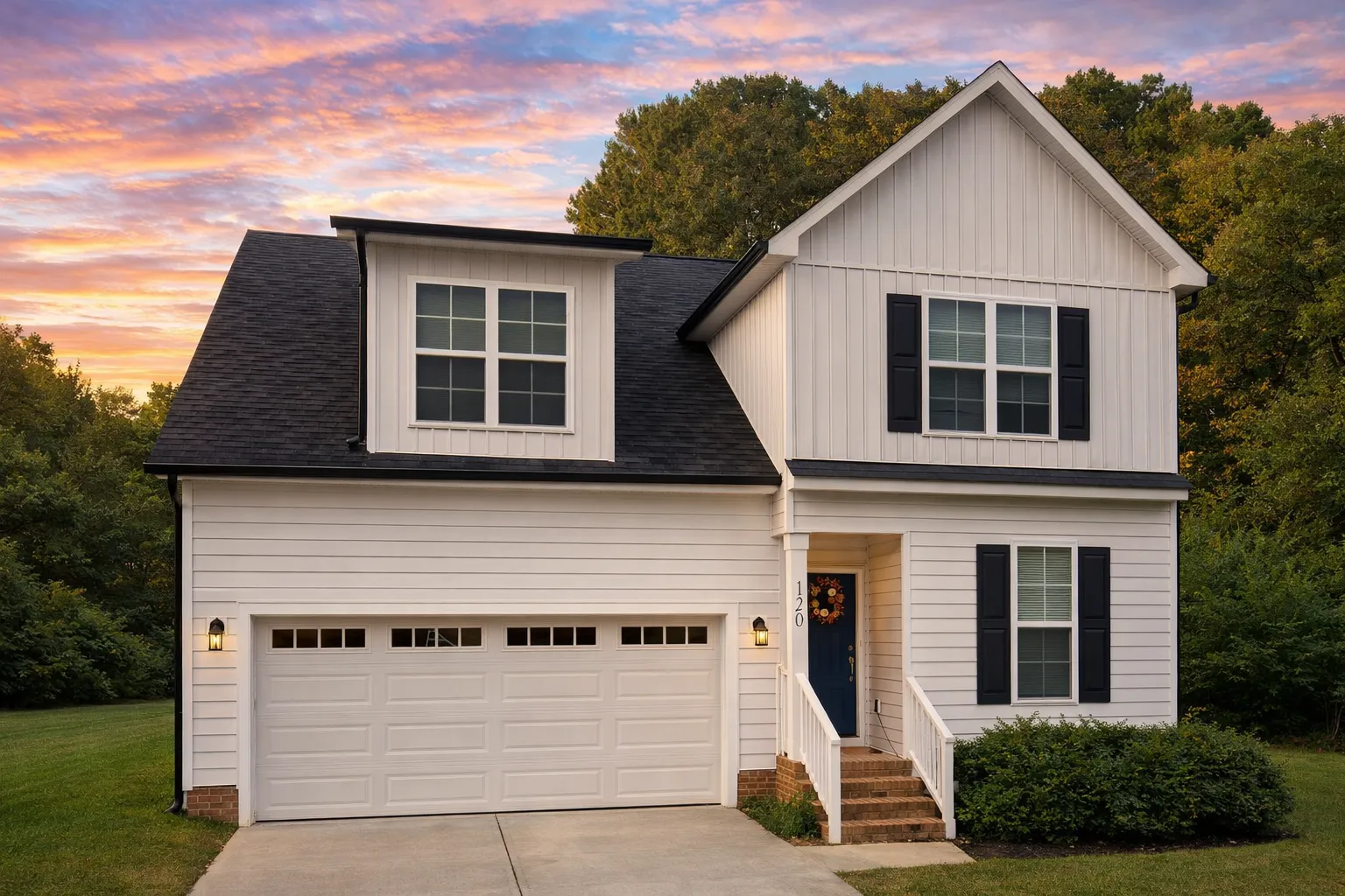Front view of a Traditional Colonial home featuring a brick exterior with board and batten siding, two stories, and a front-entry two-car garage
