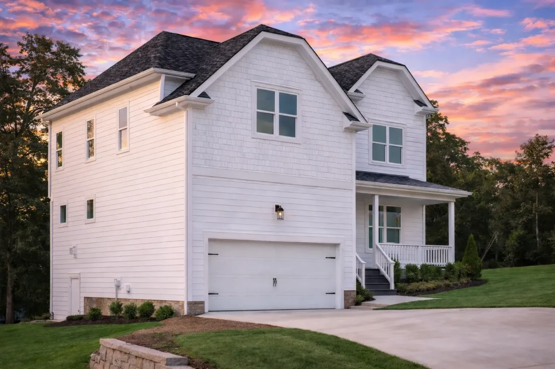 Front elevation of a Modern Farmhouse style home with white horizontal siding, gable rooflines, covered porch, and attached 2-car garage