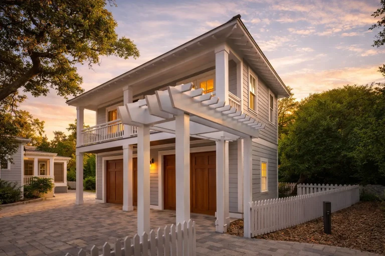 French Country Farmhouse Plans 24 Front elevation of a coastal traditional carriage house with horizontal siding, upper balcony, and decorative pergola over a two-car garage