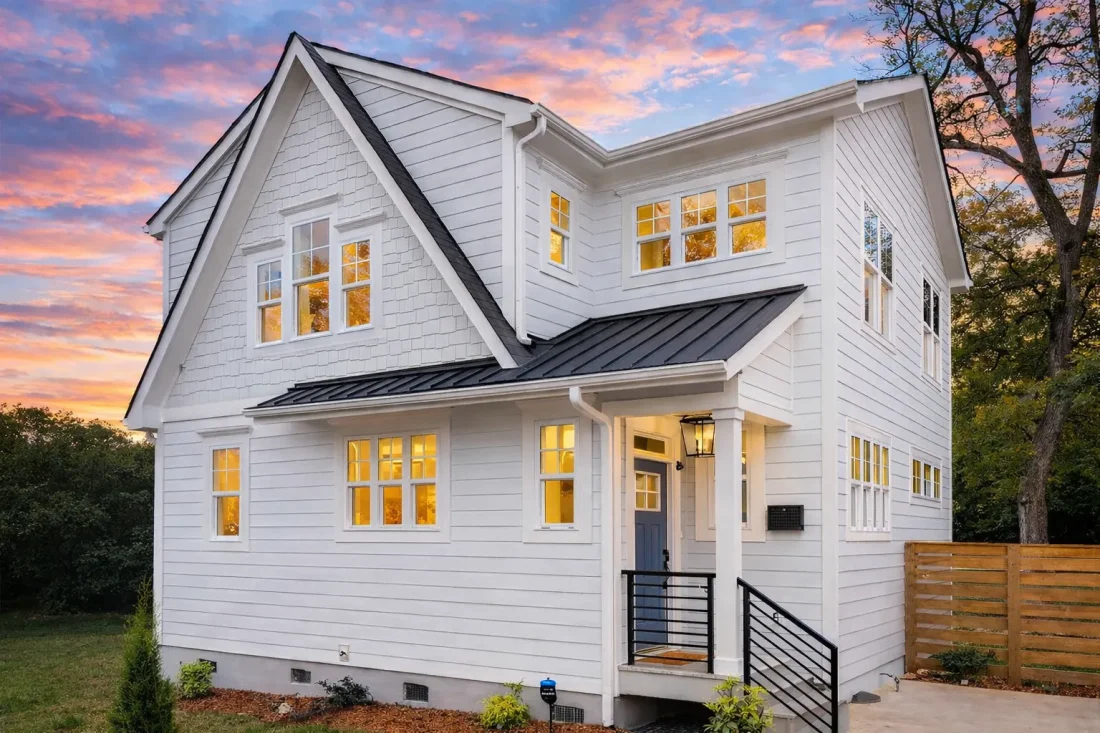 Front view of a Modern Farmhouse with horizontal lap and board and batten siding, gable rooflines, and warm evening lighting highlighting its inviting curb appeal