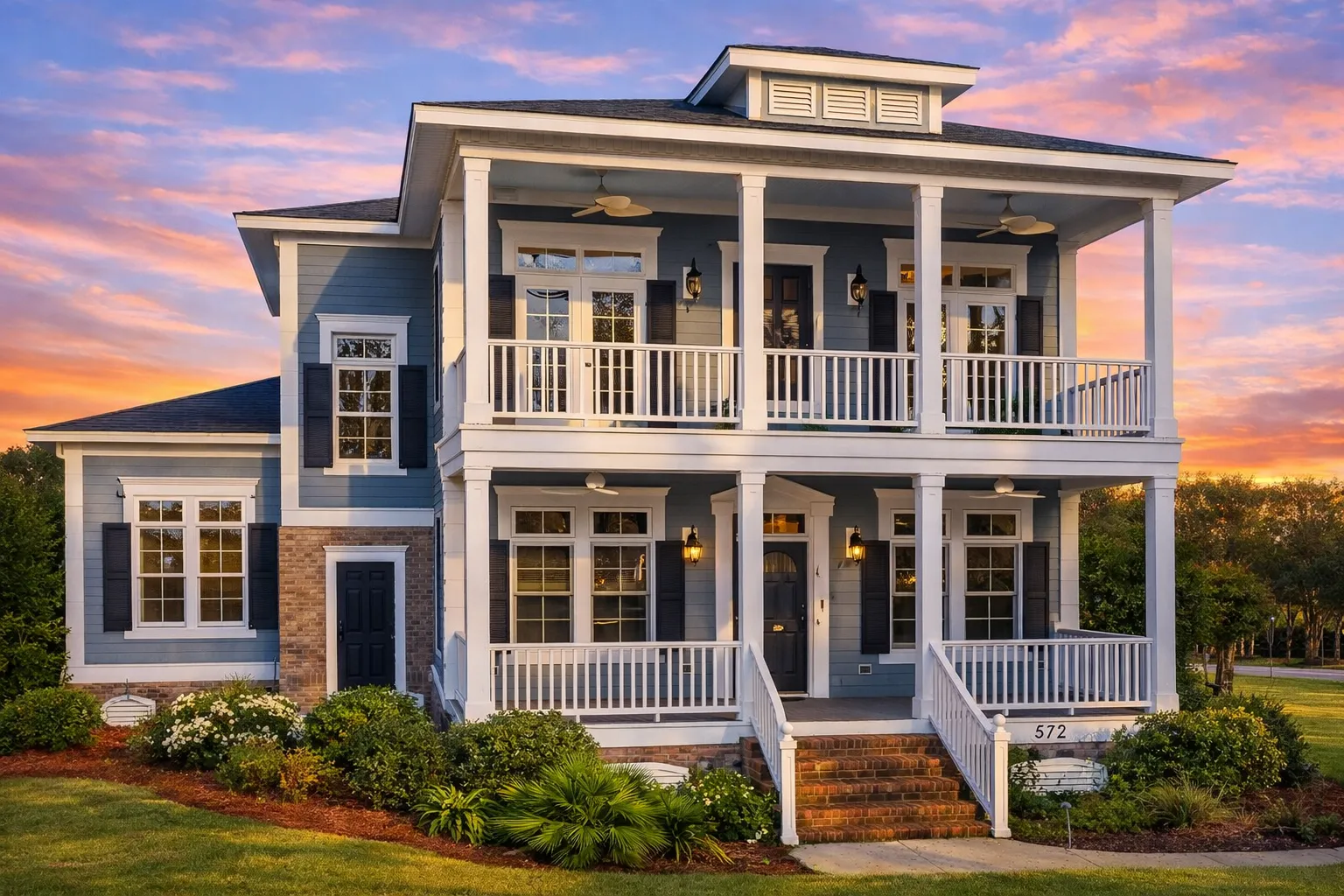 Front elevation of a Classical Southern Low Country style home with double stacked porches, brick raised foundation, horizontal siding, and symmetrical Colonial design