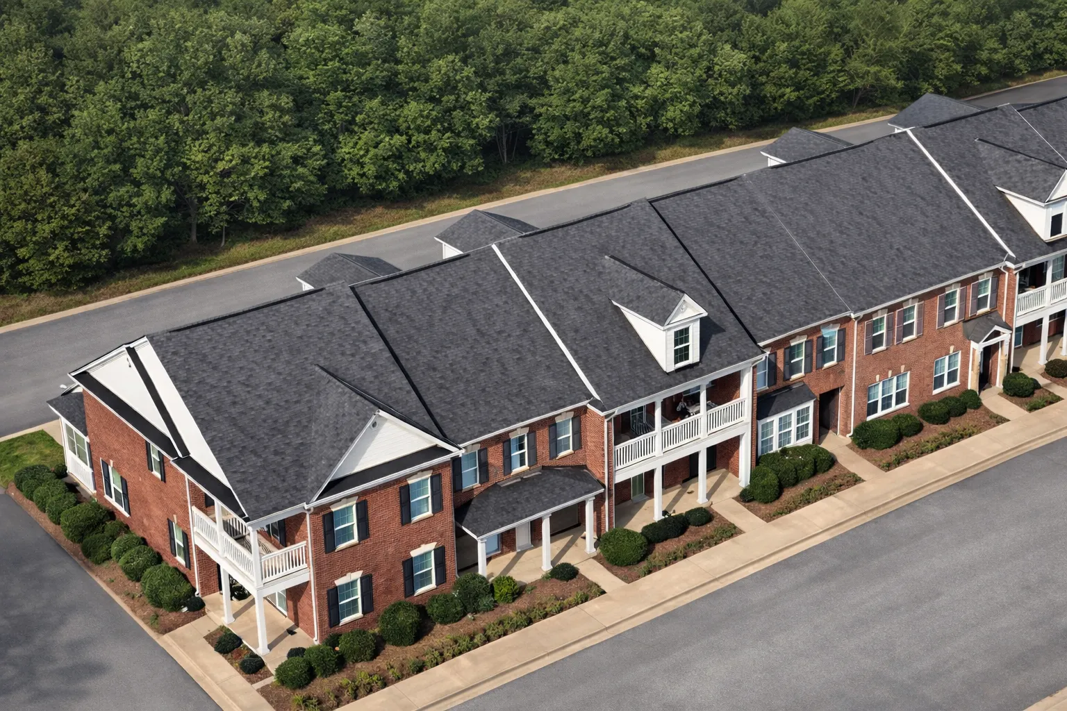 Front elevation of a Colonial and Traditional style townhome featuring symmetrical design, gable accents, and horizontal siding exterior under a dark shingle roof.